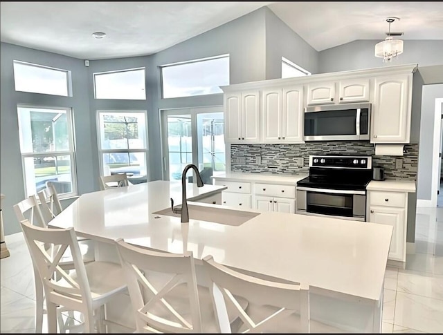 kitchen featuring tasteful backsplash, white cabinets, marble finish floor, stainless steel appliances, and light countertops