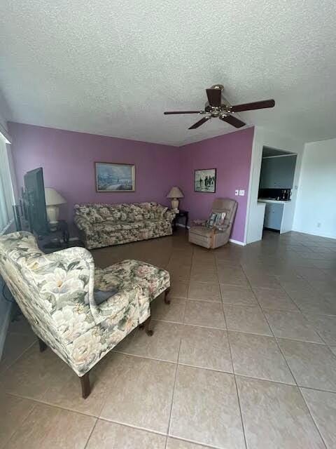 living area with tile patterned flooring, ceiling fan, and a textured ceiling