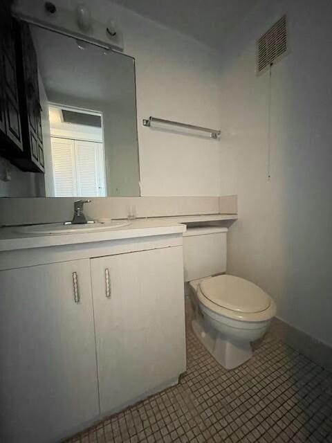 half bath with vanity, baseboards, visible vents, tile patterned floors, and toilet