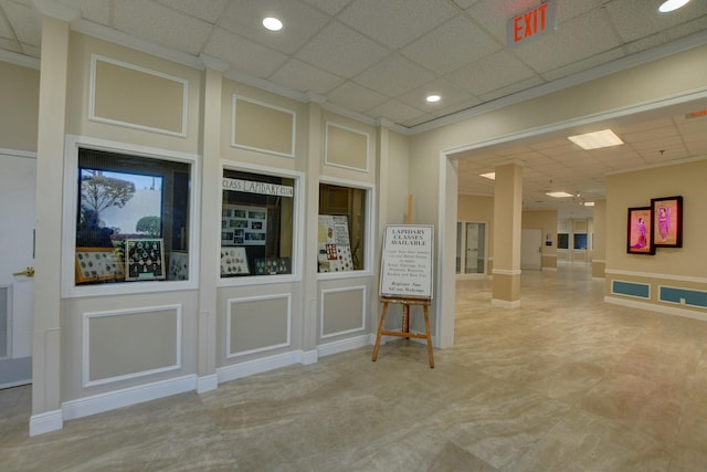 empty room with a decorative wall, a paneled ceiling, and ornate columns