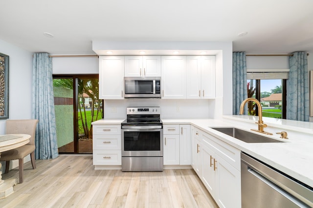 kitchen with light countertops, appliances with stainless steel finishes, light wood-type flooring, and a sink