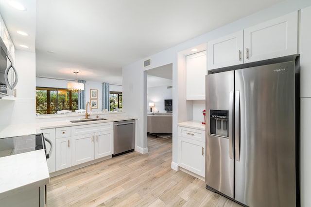 kitchen featuring stainless steel appliances, light wood finished floors, a sink, and light countertops