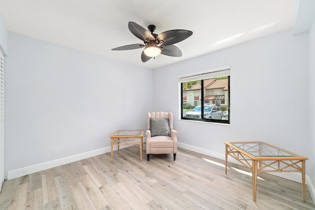 living area featuring light wood-style floors, baseboards, and a ceiling fan