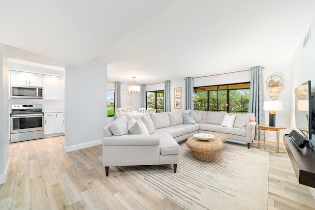 living room with baseboards, light wood finished floors, and an inviting chandelier