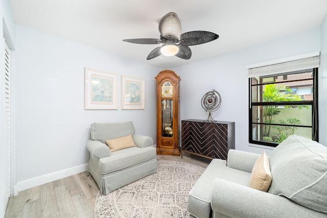 living area featuring wood finished floors, a ceiling fan, and baseboards