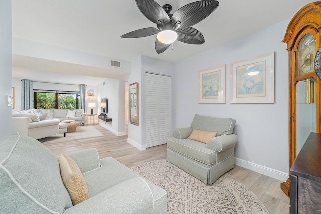 living room featuring baseboards, ceiling fan, visible vents, and light wood-style floors