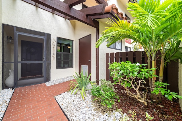 entrance to property with fence and stucco siding