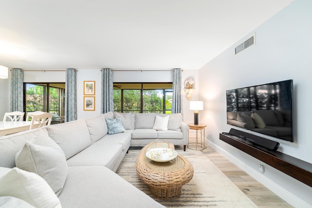 living area with a healthy amount of sunlight, light wood finished floors, baseboards, and visible vents