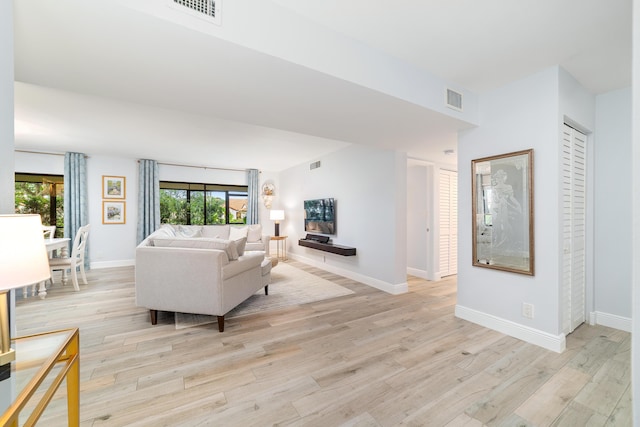 living room featuring light wood-style floors, visible vents, and baseboards