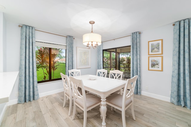 dining room featuring a chandelier, light wood-style flooring, and baseboards