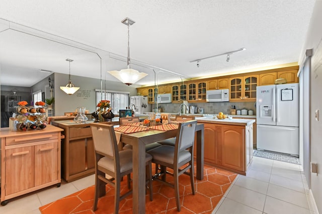 kitchen with light countertops, backsplash, glass insert cabinets, a kitchen island, and white appliances