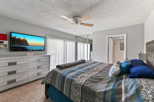 carpeted bedroom with a textured ceiling, ceiling fan, and a closet