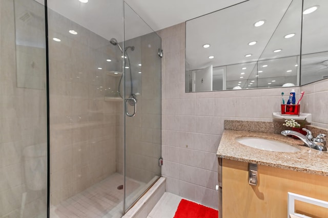 full bathroom with vanity, a shower stall, and tile walls