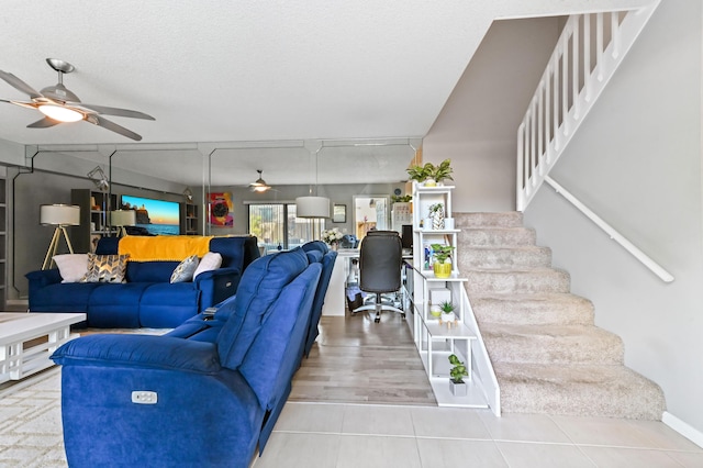 living area with stairs, ceiling fan, a textured ceiling, and tile patterned flooring