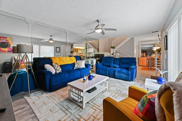 living room featuring a ceiling fan, wood finished floors, a textured ceiling, and stairs