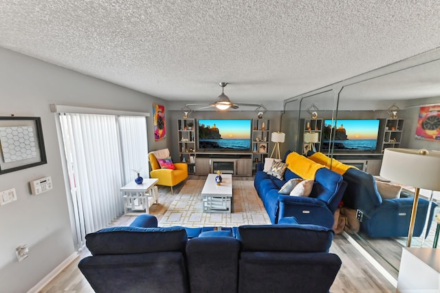 living room with ceiling fan, a textured ceiling, and wood finished floors