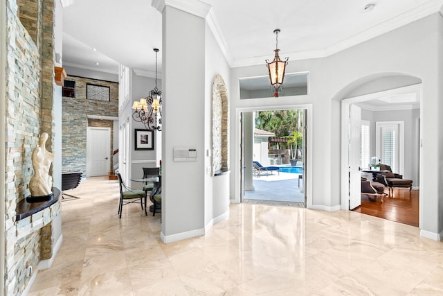 foyer entrance featuring marble finish floor, baseboards, arched walkways, and crown molding