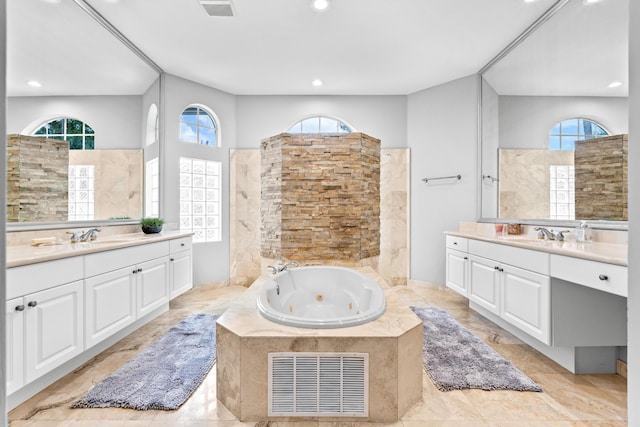 bathroom with a tub with jets, two vanities, visible vents, and recessed lighting