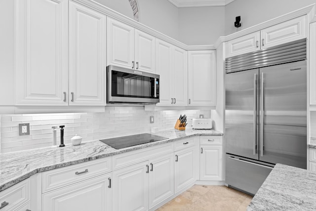 kitchen with light stone counters, appliances with stainless steel finishes, white cabinetry, and decorative backsplash