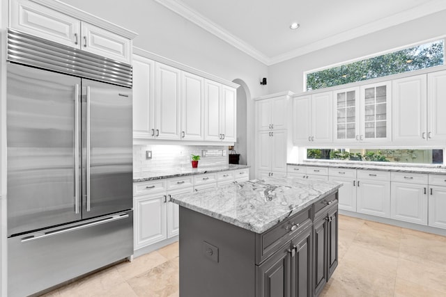 kitchen with ornamental molding, a healthy amount of sunlight, white cabinets, and stainless steel built in fridge