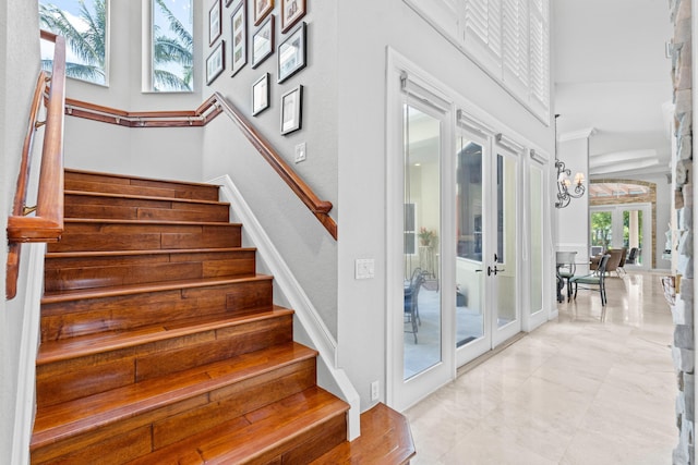 stairway with marble finish floor, a high ceiling, and french doors