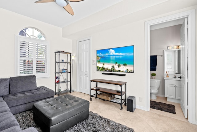 living area featuring light tile patterned floors, ceiling fan, and baseboards