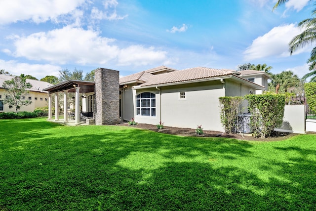 rear view of property with a tiled roof, a lawn, a patio, and stucco siding