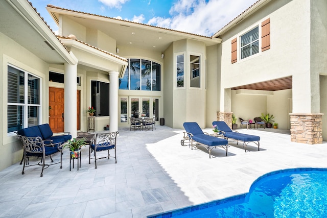 rear view of house featuring a patio area, an outdoor pool, and stucco siding