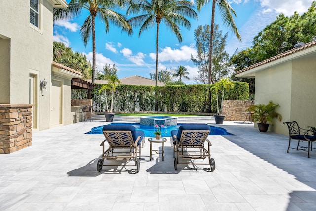 view of swimming pool featuring a pool with connected hot tub, a patio area, fence, and outdoor dry bar