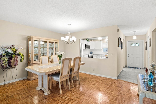 dining space with a chandelier, a textured ceiling, and baseboards