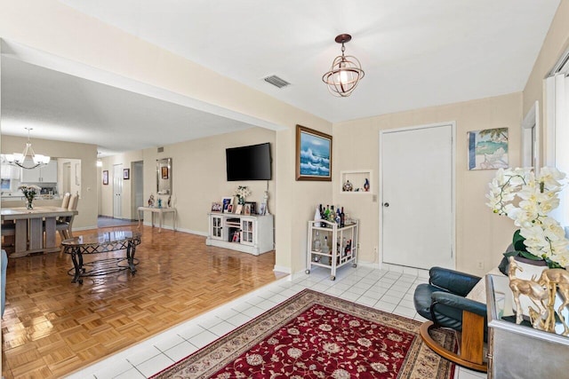 entryway with a chandelier, visible vents, baseboards, and light tile patterned floors