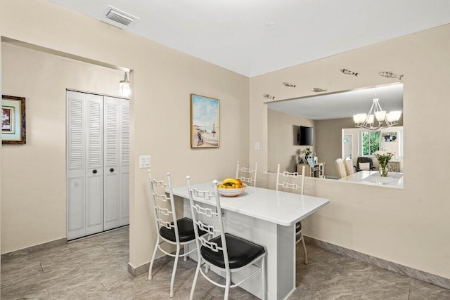 kitchen with baseboards, visible vents, a breakfast bar area, light countertops, and a notable chandelier