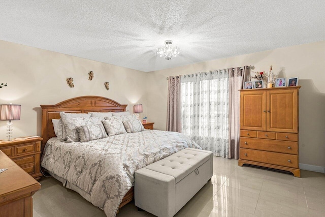 bedroom with a notable chandelier, a textured ceiling, baseboards, and light tile patterned floors