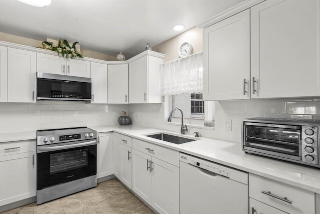 kitchen featuring a toaster, light countertops, appliances with stainless steel finishes, white cabinetry, and a sink