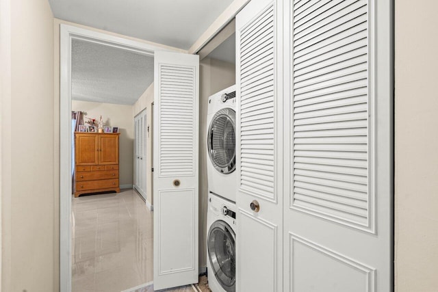 laundry room featuring stacked washer / dryer, laundry area, and a textured ceiling