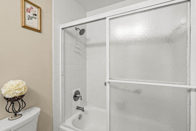 bathroom featuring enclosed tub / shower combo and toilet