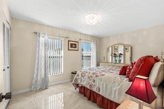 bedroom featuring access to exterior, a closet, a textured ceiling, and baseboards