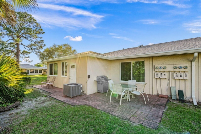 rear view of property with a shingled roof, a lawn, a patio area, and cooling unit