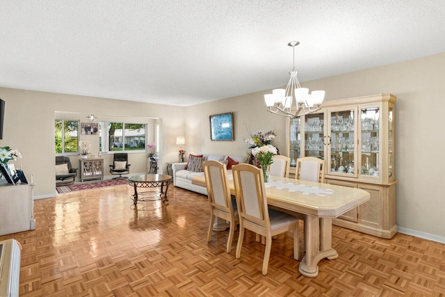 dining room featuring a notable chandelier, a textured ceiling, and baseboards