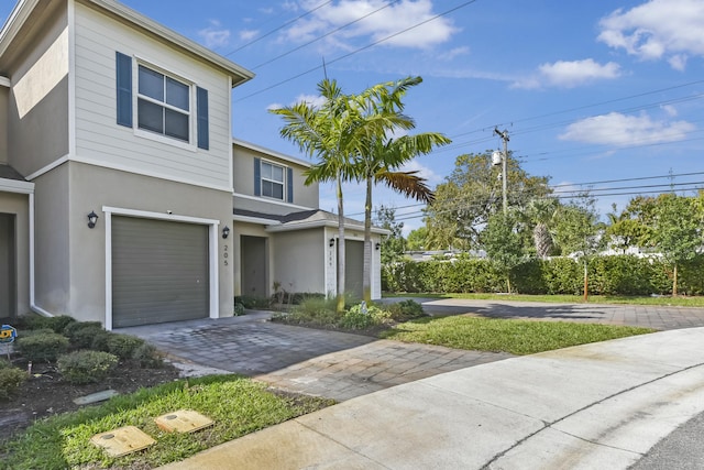 view of front facade featuring a garage, decorative driveway, and stucco siding