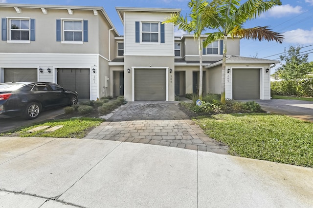 townhome / multi-family property featuring decorative driveway and stucco siding