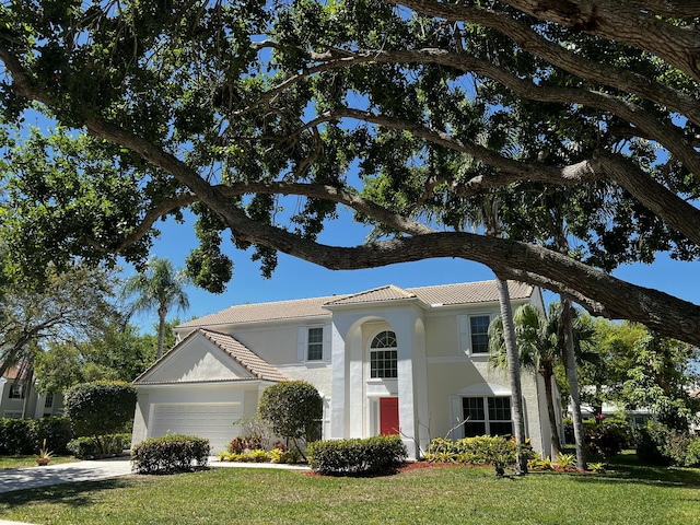 view of front of property featuring a tile roof, stucco siding, a garage, driveway, and a front lawn