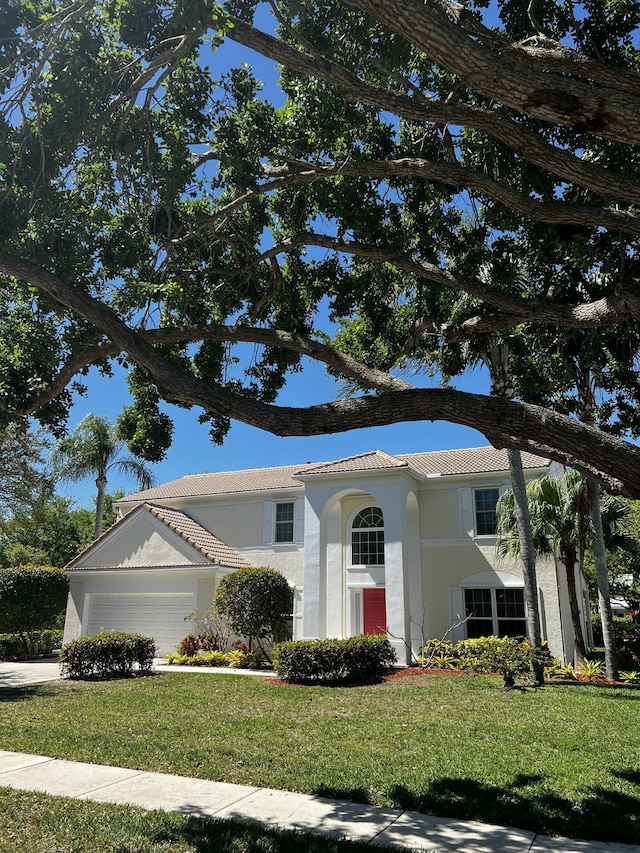 view of front facade with a front lawn, a tile roof, an attached garage, and stucco siding