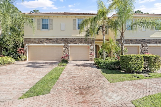 view of front of house with a tile roof, a garage, driveway, and stucco siding