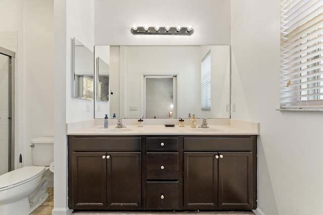 full bath featuring a sink, an enclosed shower, toilet, and double vanity