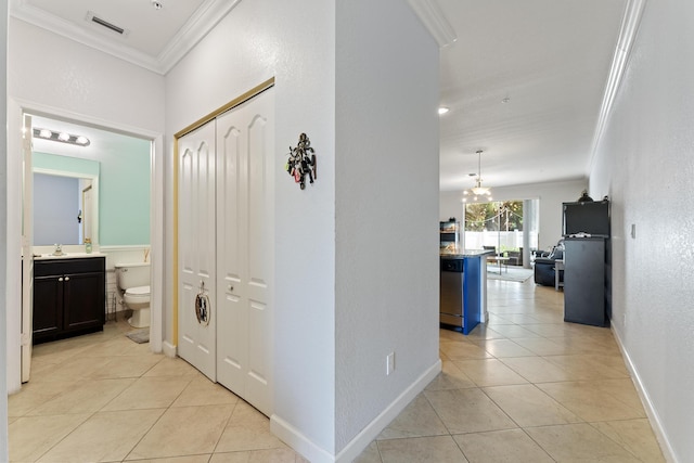 hallway featuring light tile patterned floors, visible vents, crown molding, and a sink