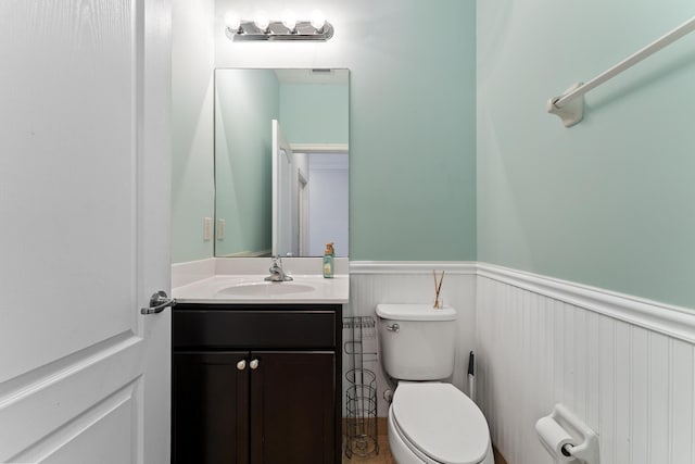 bathroom with vanity, toilet, and wainscoting