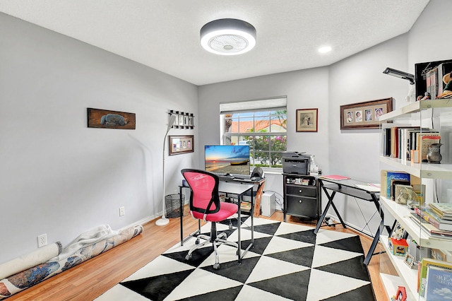 home office with a textured ceiling, baseboards, and wood finished floors