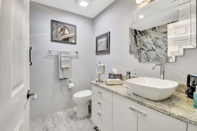 bathroom with toilet, baseboards, wood finished floors, and vanity