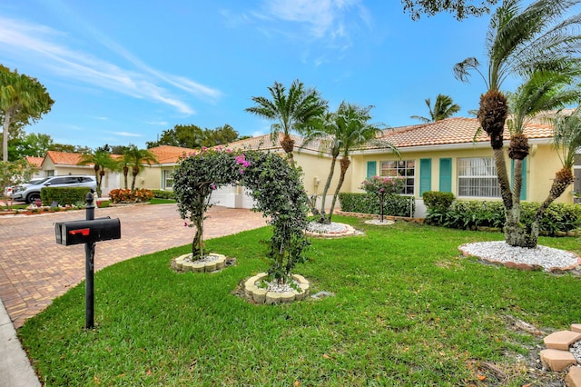 ranch-style house with a tile roof, an attached garage, decorative driveway, a front lawn, and stucco siding